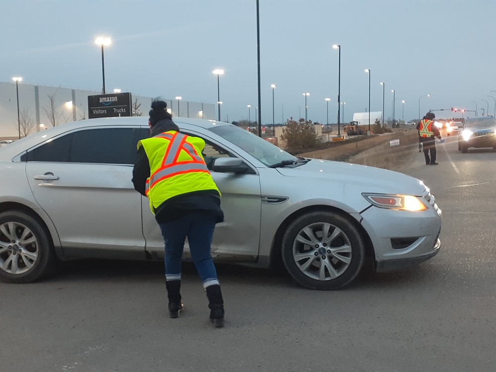 Car stopped in front of the Amazon YEG1 facility getting a handout.
